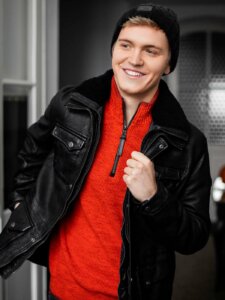 Schwarze Lederjacke Klassiker Junger Mann trägt schwarze Lederjacke und roten Pullover