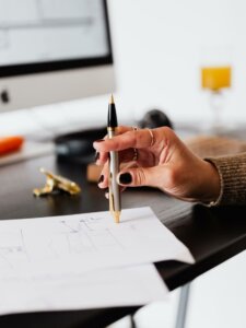 Damenhand tippt mit Stift auf Papier