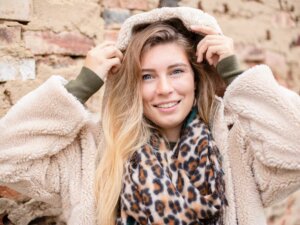 Teddyjacke im Winter Junge Frau trägt helle Teddyjacke und zieht sich lächelnd die Kapuze über