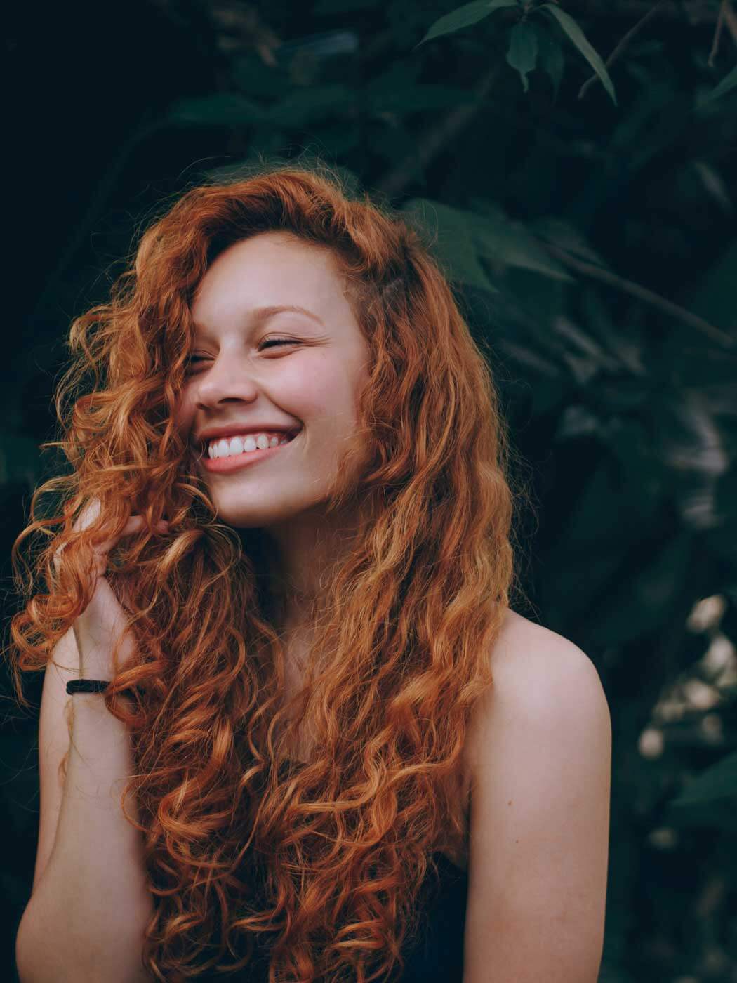 Lachende Frau mit roten, lang gelockten Haaren
