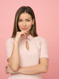 damen-modetrends-2022 Junge Frau trägt rosafarbenes Oberteil mit Schlitz unter dem Kragen