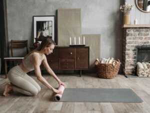 Faszien massieren Junge Frau rollt Yogamatte im Wohnzimmer aus