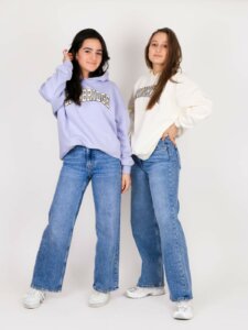 Zwei junge Frauen in weiten Jeans und Pullover in Pastellfarben