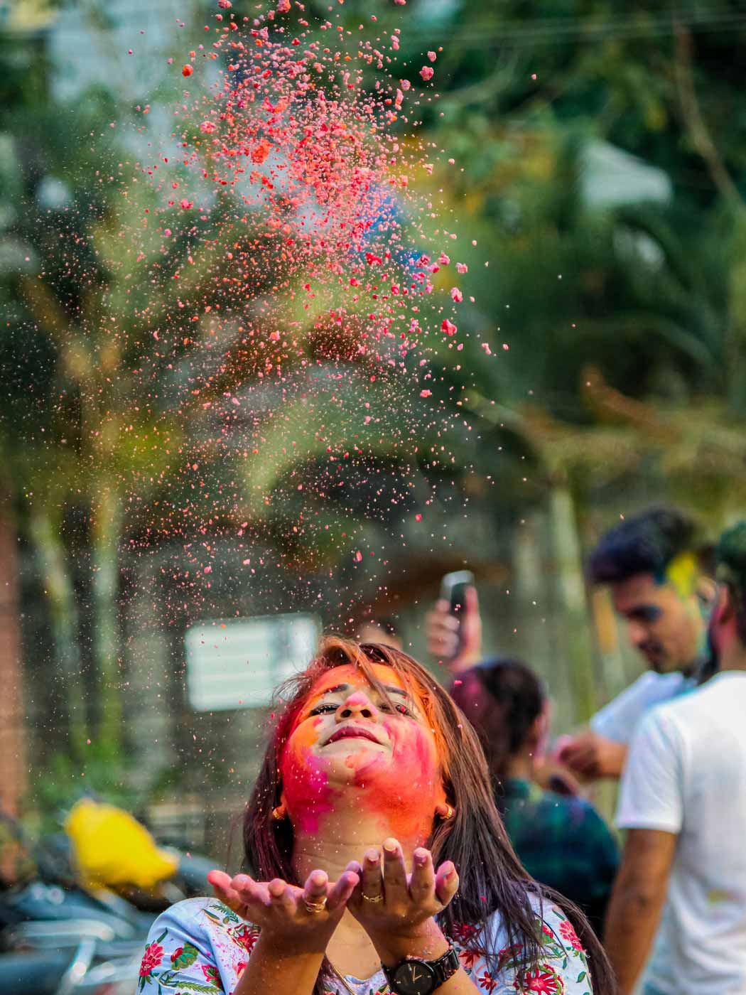 Frau mit rotem Gesicht pustet Farbpulver in die Luft
