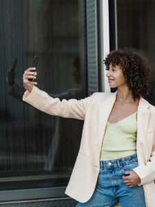 Junge Frau lächelt in die Kamera ihres Smartphones und macht Selfie