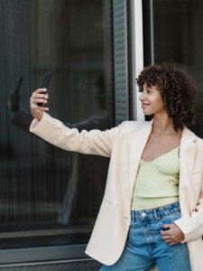 Selfie machen lächeln Junge Frau lächelt in die Kamera ihres Smartphones und macht Selfie