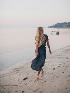 Frau im Kleid läuft am Strand entlang