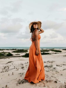 Hautpflege Sommer Frau im orangenen Kleid am Strand