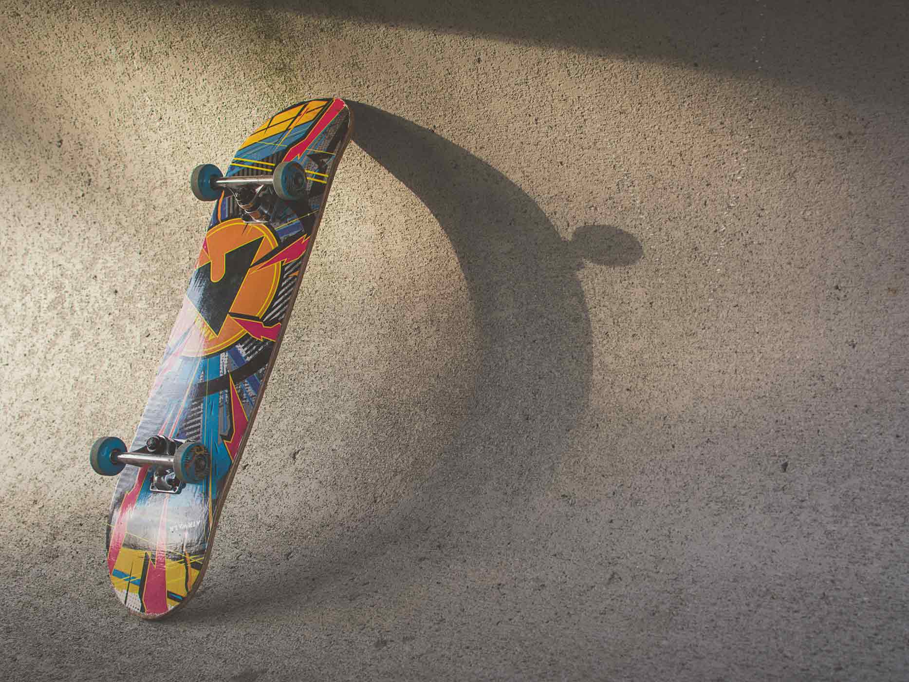 Buntes Skateboard lehnt in einer Bowl mit der Oberseite an der Wand