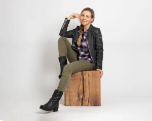 Damen Layering Look Frau posiert und trägt einen herbstlichen Look, bestehend aus Stiefel, Jeans, Bluse und Lederjacke