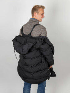 Funktionale Herrenjacke Junger Mann trägt eine Jacke mit Schultergurt