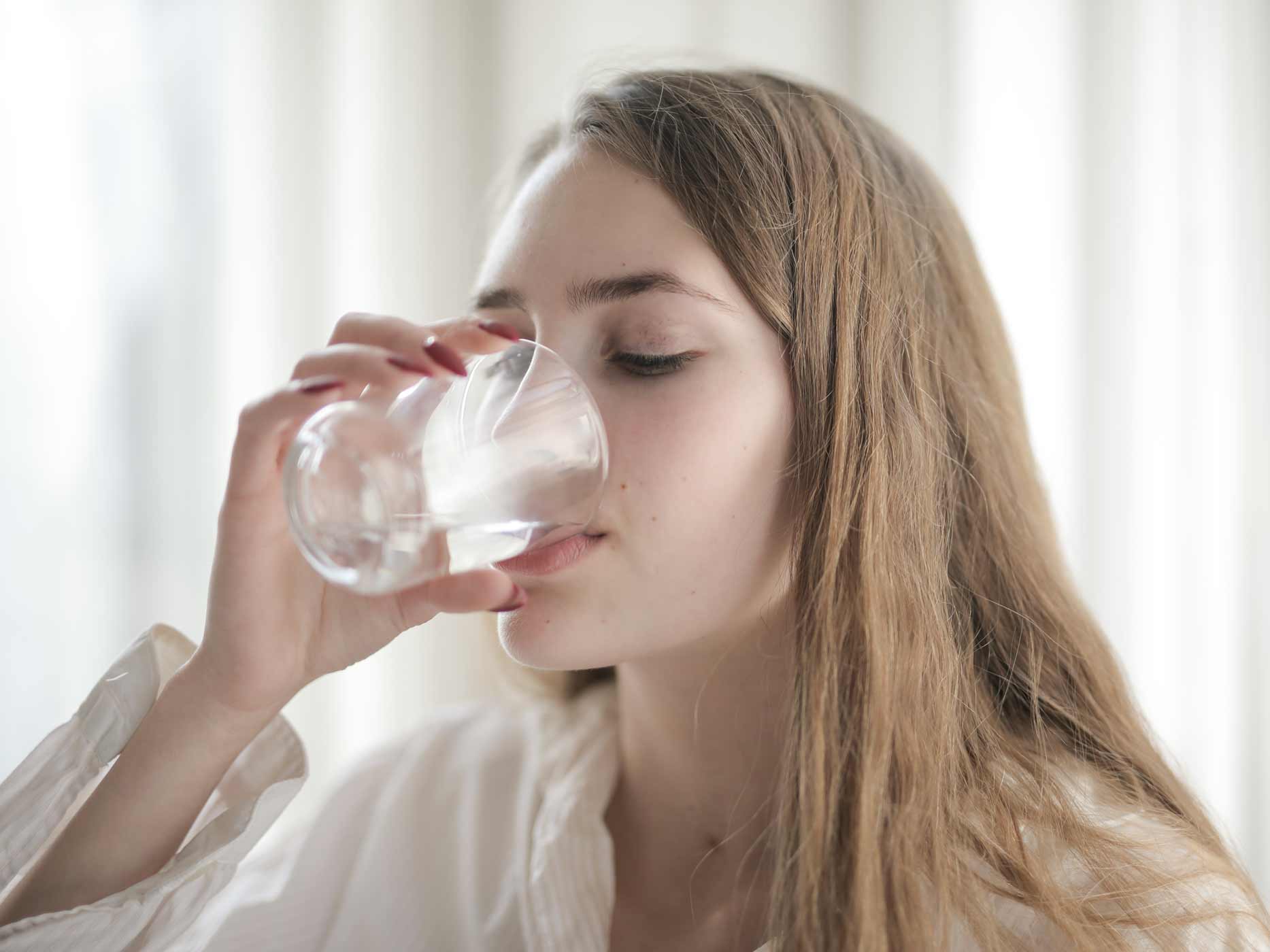 Frau trinkt aus einem Wasserglas