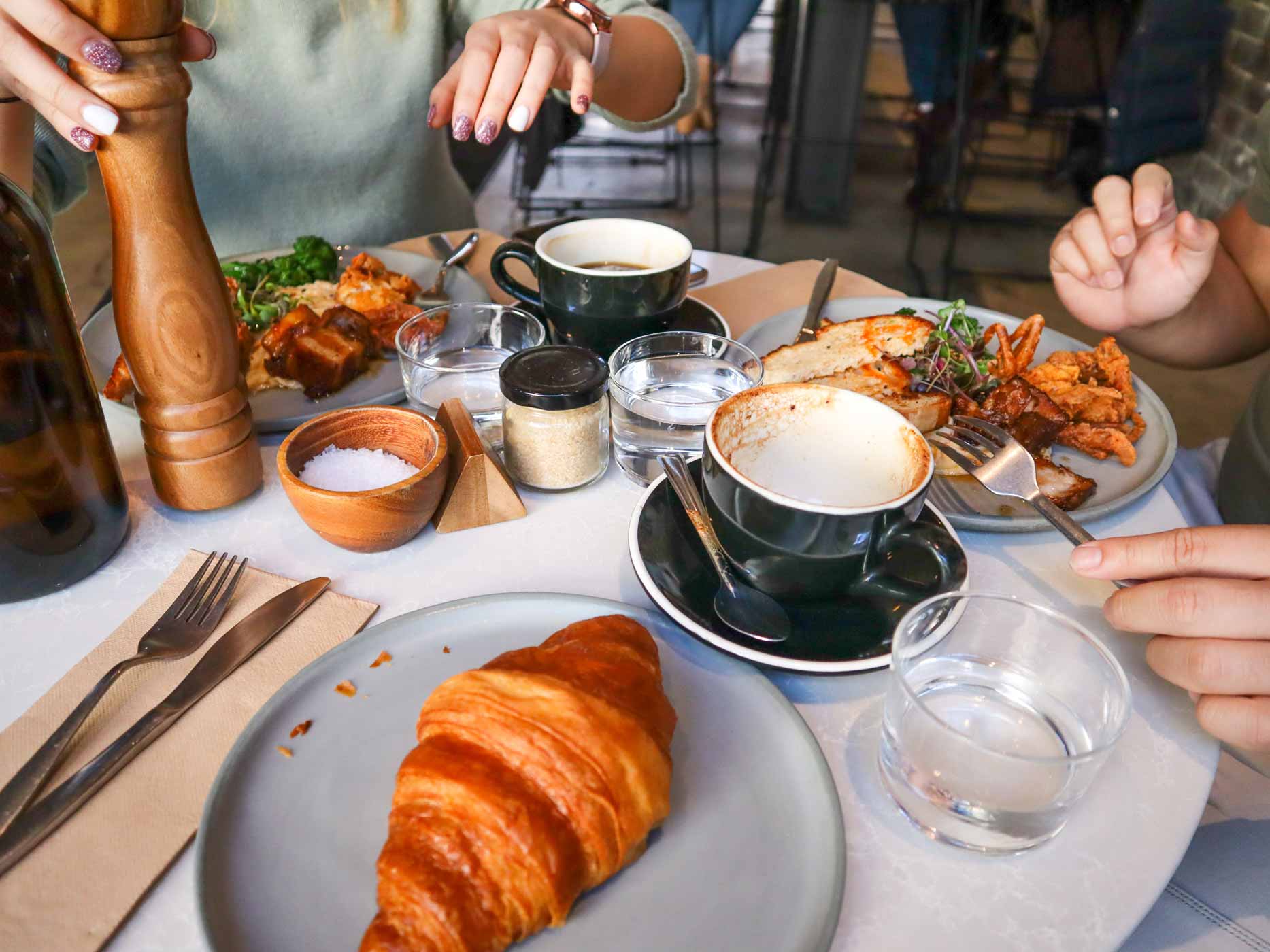 Gedeckter Frühstückstisch mit Croissant, Kaffee und herzhaften Speisen
