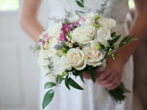 Braut hält einen Brautstrauß aus cremeweißen Rosen