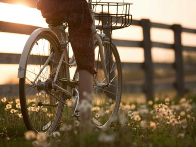 Eine Frau fährt auf einem Fahrrad im Sonnenuntergang auf einer Blumenwiese entlang