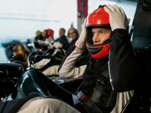Mann in einem Kart auf der Rennbahn, der sich den Helm aufsetzt