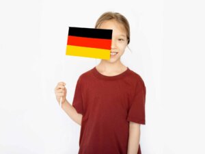 Fußball EM Party Mädchen in rotem Shirt hält sich eine Deutschlandflagge halb vors Gesicht