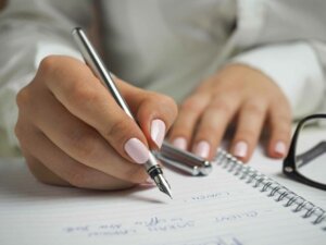 Finanzen verwalten Nahaufnahme weiblicher Hände, die einen Füller halten und in einen Block schreiben
