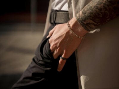 Mann trägt schwarzen Ring und goldenes Armband
