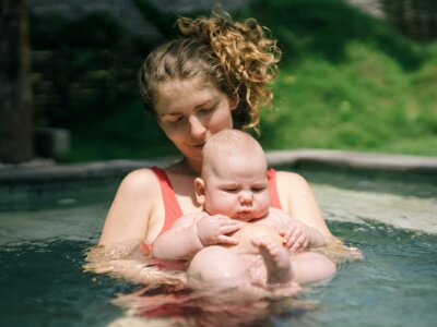 Frau hält ihr Baby im Wasser im Arm