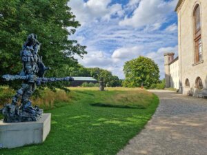 Skulptur im Schlosspark an einem Weg, der an der Schlossmauer vorbeiführt