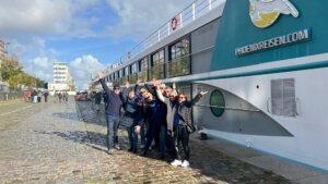 Eine kleine Reisegruppe steht vor einem Flusskreuzfahrtschiff.