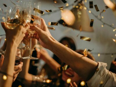 Mehrere Gläser werden zum Anstoßen benutzt; es regnet goldenes Konfetti