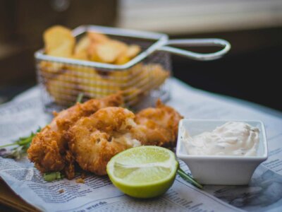 Ein Bild von Fish'n-Chips mit einer Limette und Soße daneben.