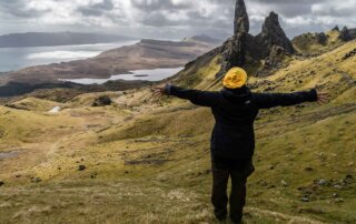 Eine Frau steht in den Highlands und streckt die Arme aus.