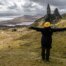 Eine Frau steht in den Highlands und streckt die Arme aus.